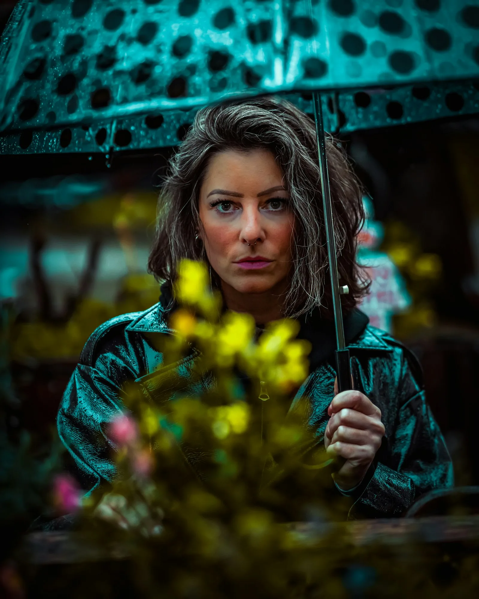 A woman with an umbrella in the rain, lit in teal