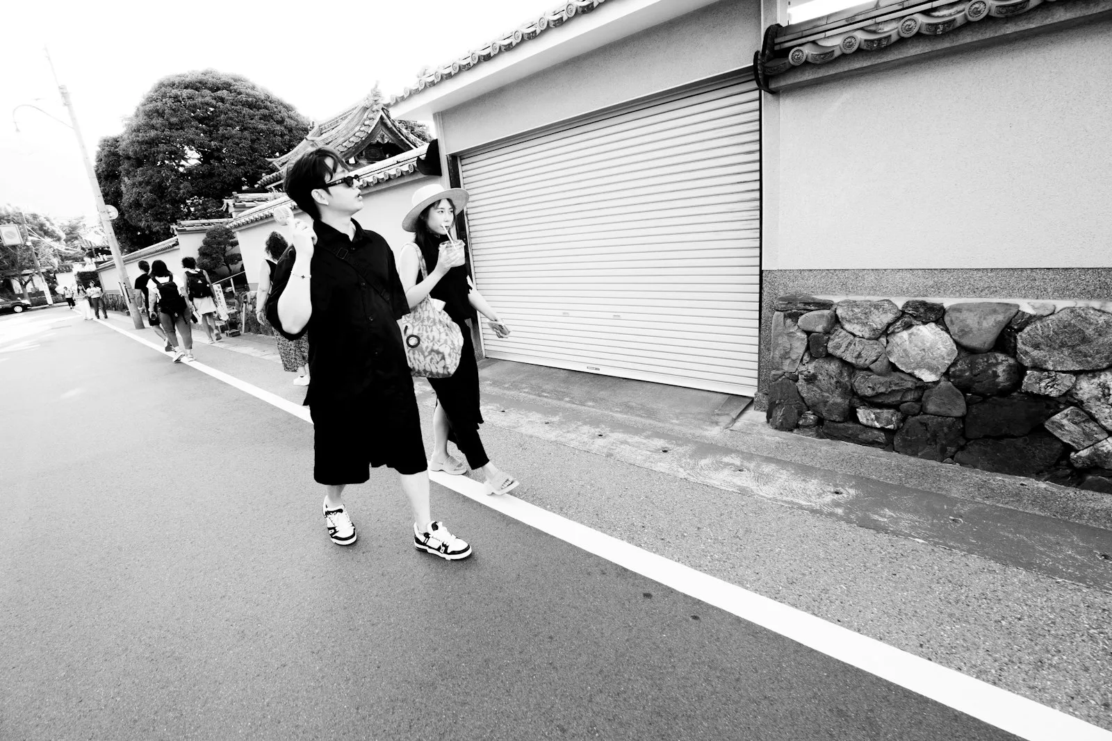 Walking past an old stone wall, in black and white