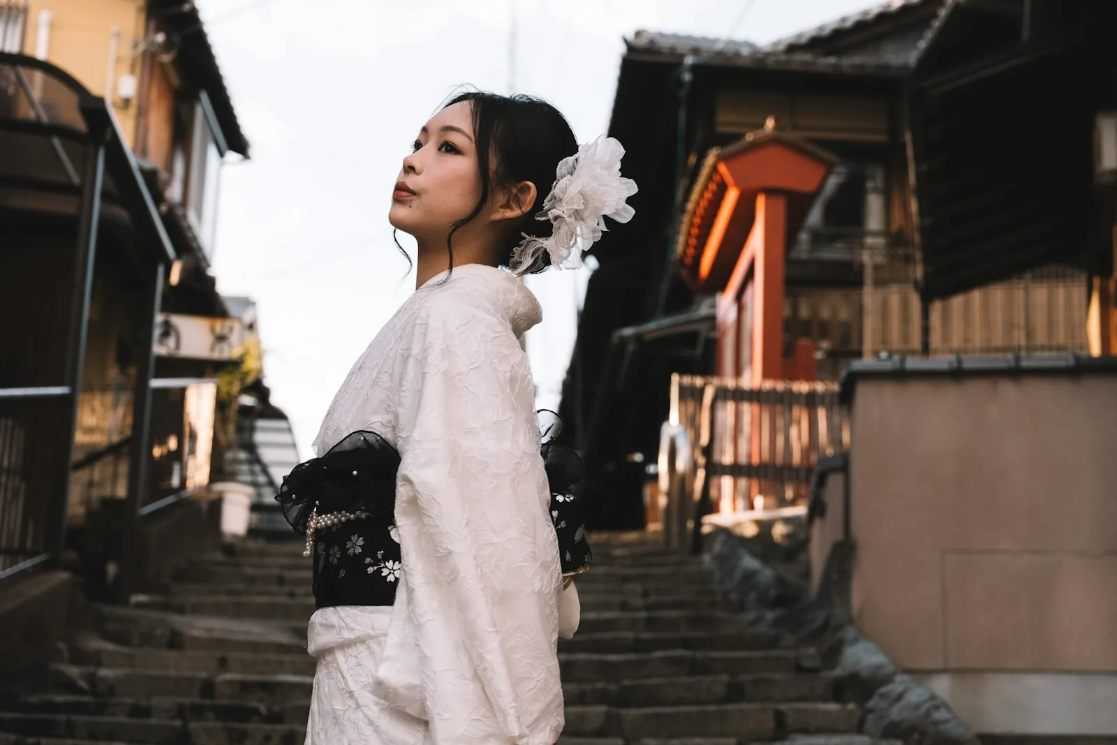 A woman in a white kimono walking up stone steps